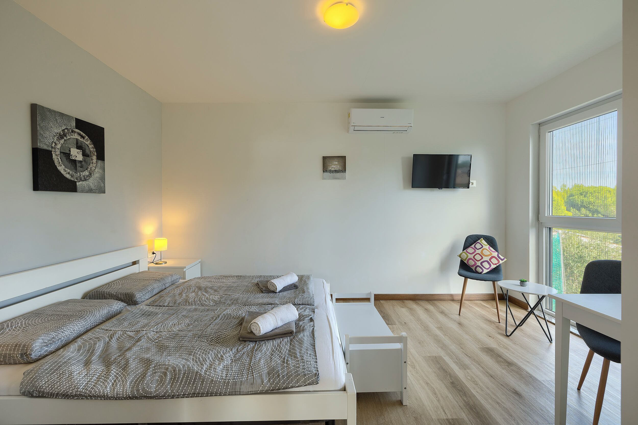 A modern bedroom with a bed, bedside tables, a desk, and a chair.