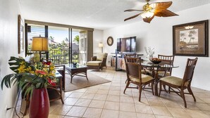 A spacious living area with a dining table, chairs, a TV, and a ceiling fan.