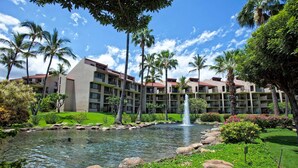 A hotel with multiple buildings, a central water feature, and lush greenery.