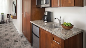A compact kitchen with wooden cabinets, a granite countertop, a stainless steel sink, a microwave, and a coffee maker. - Marriott's Shadow Ridge - Enclaves - 2 Bedroom (Palm Desert)