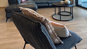 Ein modernes Wohnzimmer mit einem Ecksofa, einem runden Couchtisch und einem Gemälde eines Segelboots.