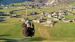 A person on a swing overlooking a village with mountains in the background. - Vacation cottage FuchsbAU, Austria (Au)