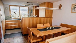 A compact kitchen with wooden cabinets, a dining table, and a small island. - Vacation cottage FuchsbAU, Austria (Au)