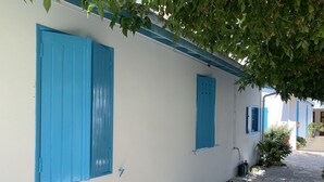 Ein weißes Gebäude mit blauen Fensterläden und einem gepflasterten Weg.