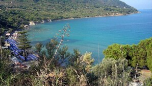 A coastal view with a beach, a mountain, and a row of blue umbrellas. - Belvilla by OYO Villa Martina (Agropoli)
