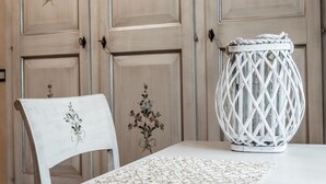 A white chair with floral embroidery, a white woven table lamp, and a table with a woven placemat. - Belvilla by OYO Villa Martina (Agropoli)