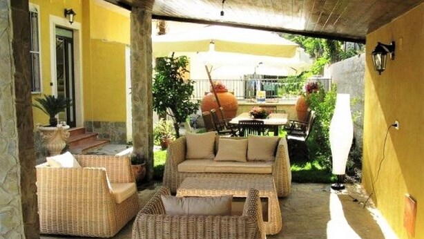 An outdoor patio with wicker furniture, a sofa, and a table. - Belvilla by OYO Villa Martina (Agropoli)
