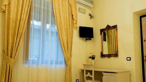 A room with a bed, a desk with a chair, a television, a mirror, and a window with curtains. - Belvilla by OYO Villa Martina (Agropoli)