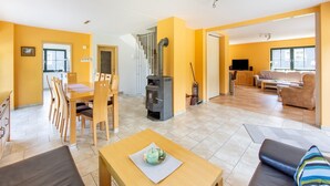 A spacious living area with a dining table and chairs, a sofa, and a fireplace. - Rennsteig Trail Family Escape (Eisfeld)