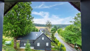 A black house with a sloped roof, surrounded by trees and a road. - Rennsteig Trail Family Escape (Eisfeld)