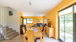 A modern kitchen with a dining area, featuring a large window, a built-in stove, and a staircase leading to another level. - Rennsteig Trail Family Escape (Eisfeld)