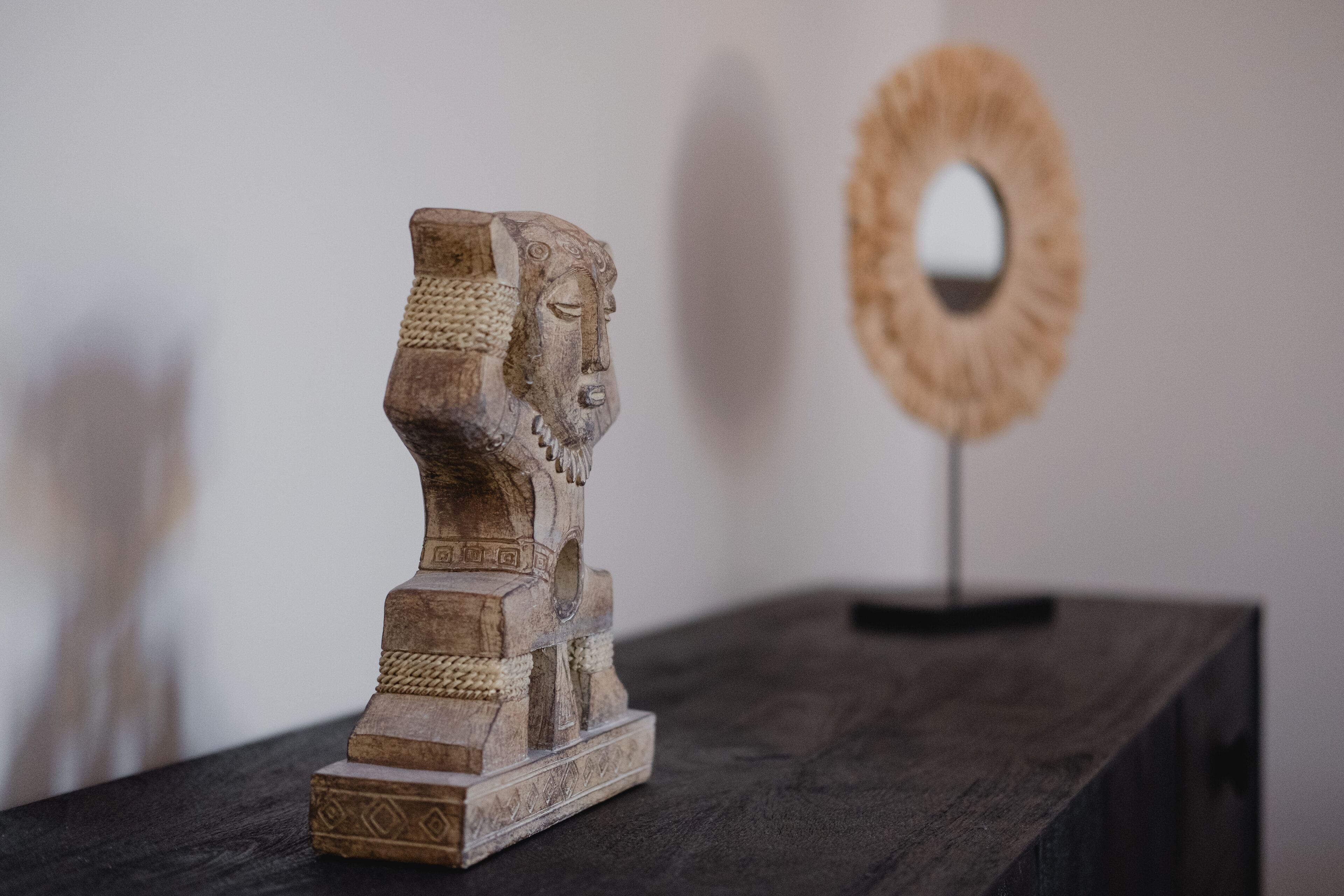 A wooden sculpture of a human head on a dark wooden table.