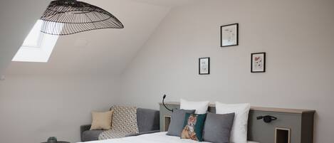 A modern bedroom with a large bed, a side table, a small round table, and a ceiling light fixture.