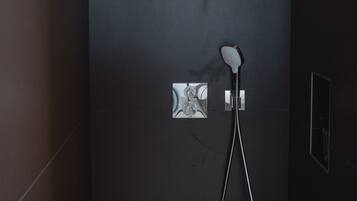 A modern shower area with a handheld showerhead and a wall-mounted control panel.