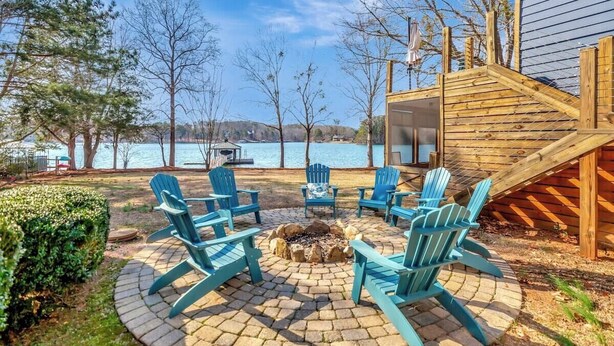 A patio with a fire pit and Adirondack chairs, overlooking a lake. - Sunset Ridge Lake Front Retreat (Seneca)