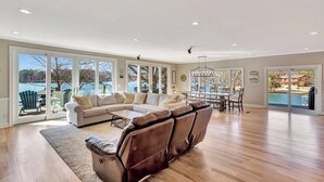 A spacious living room with a large sectional sofa, a dining area, and a view of a lake. - Sunset Ridge Lake Front Retreat (Seneca)