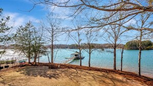 A lakeside view with a dock, trees, and a grassy area. - Sunset Ridge Lake Front Retreat (Seneca)