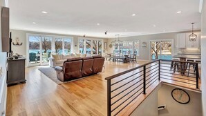 A spacious living area with a wooden floor, a brown sofa, and a dining table with chairs. - Sunset Ridge Lake Front Retreat (Seneca)