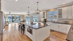 A spacious kitchen with a large island, white cabinetry, and pendant lighting. - Sunset Ridge Lake Front Retreat (Seneca)