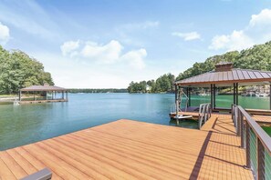 A wooden deck with a gazebo and a covered area overlooking a calm lake.