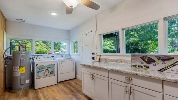 A kitchen with a washer and dryer, a countertop with a box, and large windows.