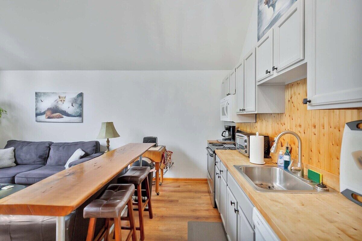 A compact kitchen with a wooden countertop, white cabinets, and a sink.