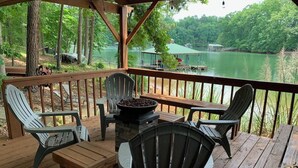 Une terrasse en bois avec des meubles d’extérieur, un foyer et une vue sur un lac.