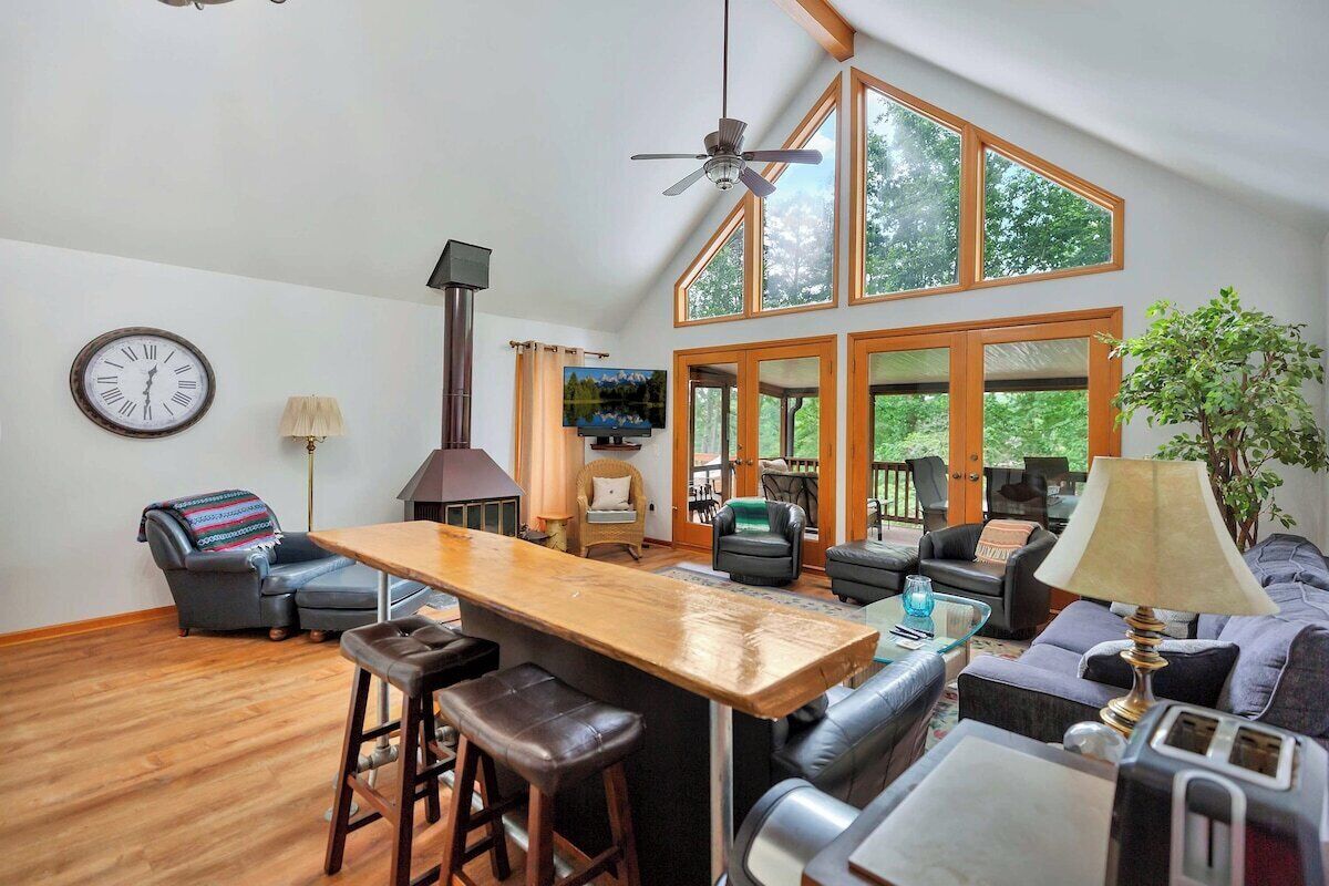 A spacious living area with a wooden bar, leather seating, and large windows offering a view of the outdoors.