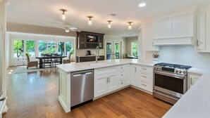 A spacious kitchen with white cabinetry, a stainless steel dishwasher, and a built-in oven.
