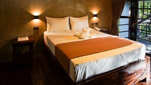 Una cama grande con cabecera de madera, dos lámparas de noche y una mesita de noche con un teléfono.