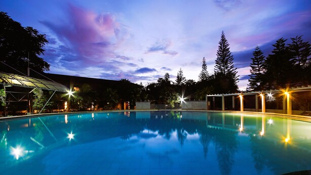 Una piscina con vistas claras a los árboles circundantes y un cielo al atardecer.