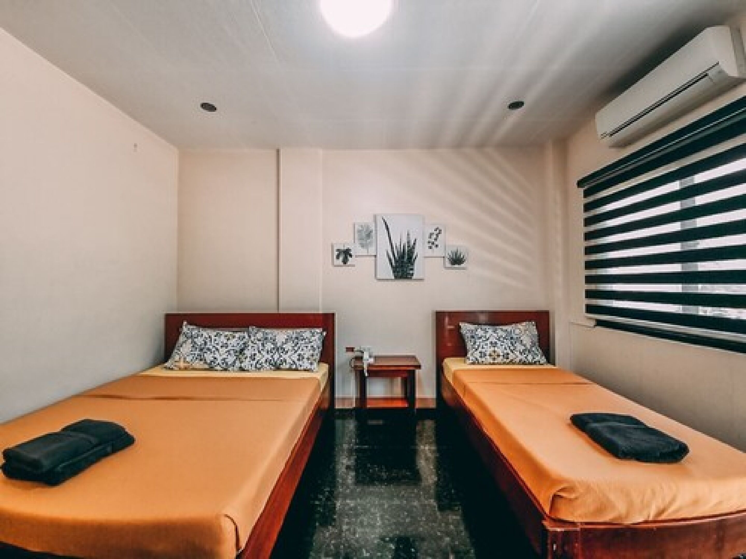 Une chambre avec deux lits simples, une petite table et un climatiseur fixé au mur.