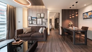 A modern living room with a sofa, a dining table, and a kitchen area. - Aspira Parc Sukhumvit 22 (Bangkok)