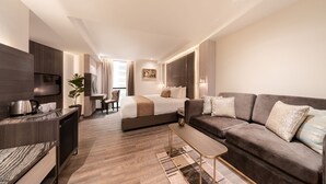 A modern hotel room with a bed, sofa, coffee table, and a small dining area. - Aspira Parc Sukhumvit 22 (Bangkok)