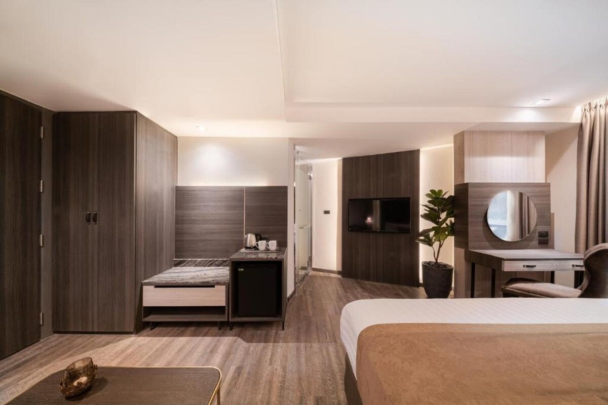 A modern hotel room with a bed, desk, and wardrobe.
