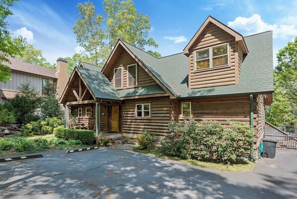 A log cabin with a front porch, a chimney, and a well-maintained garden. - Massive Lake Keowee Knox Campground Cabin (Seneca)