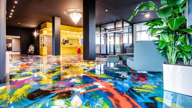 Un vestíbulo moderno con un piso colorido, una recepción y una planta grande.