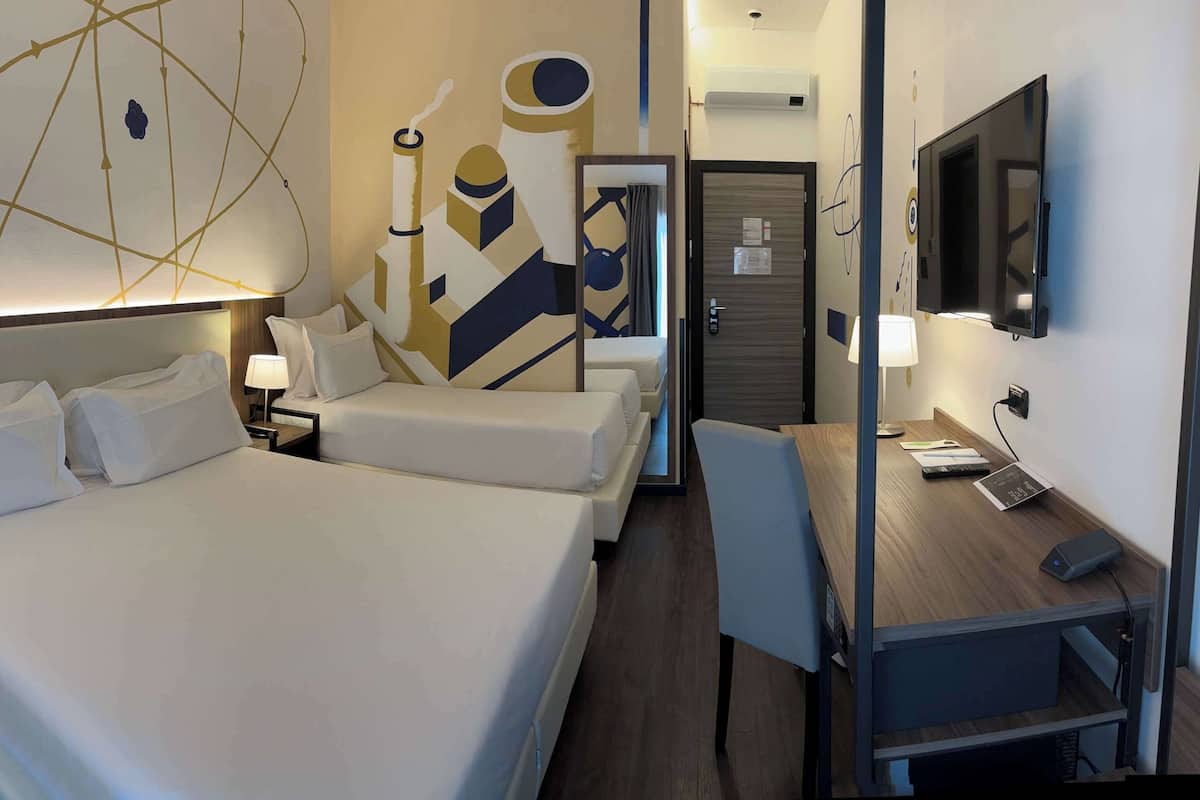 A hotel room with a large bed, a desk with a chair, a TV, and a wall with abstract art.