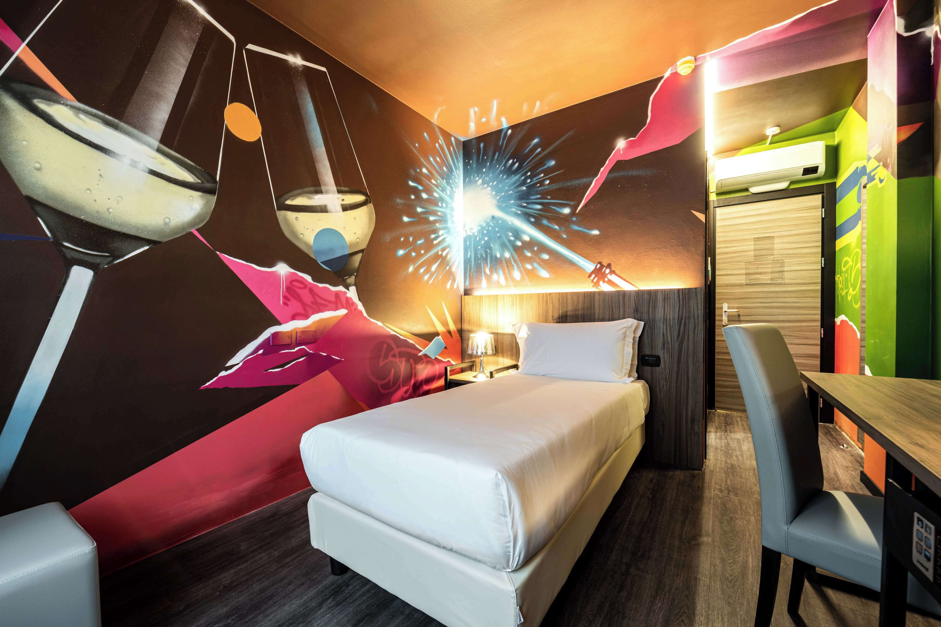 A modern hotel room with a bed, a desk, and a chair.