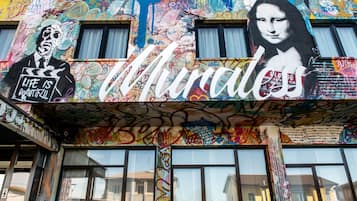 A building facade covered with colorful graffiti and murals, including a prominent depiction of the Mona Lisa.