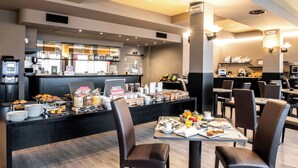 Un área de desayuno con mostrador que exhibe diferentes alimentos y un espacio de comedor con mesas y sillas.