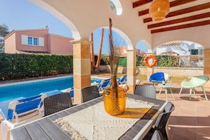 A poolside area with a table, chairs, and a decorative vase.