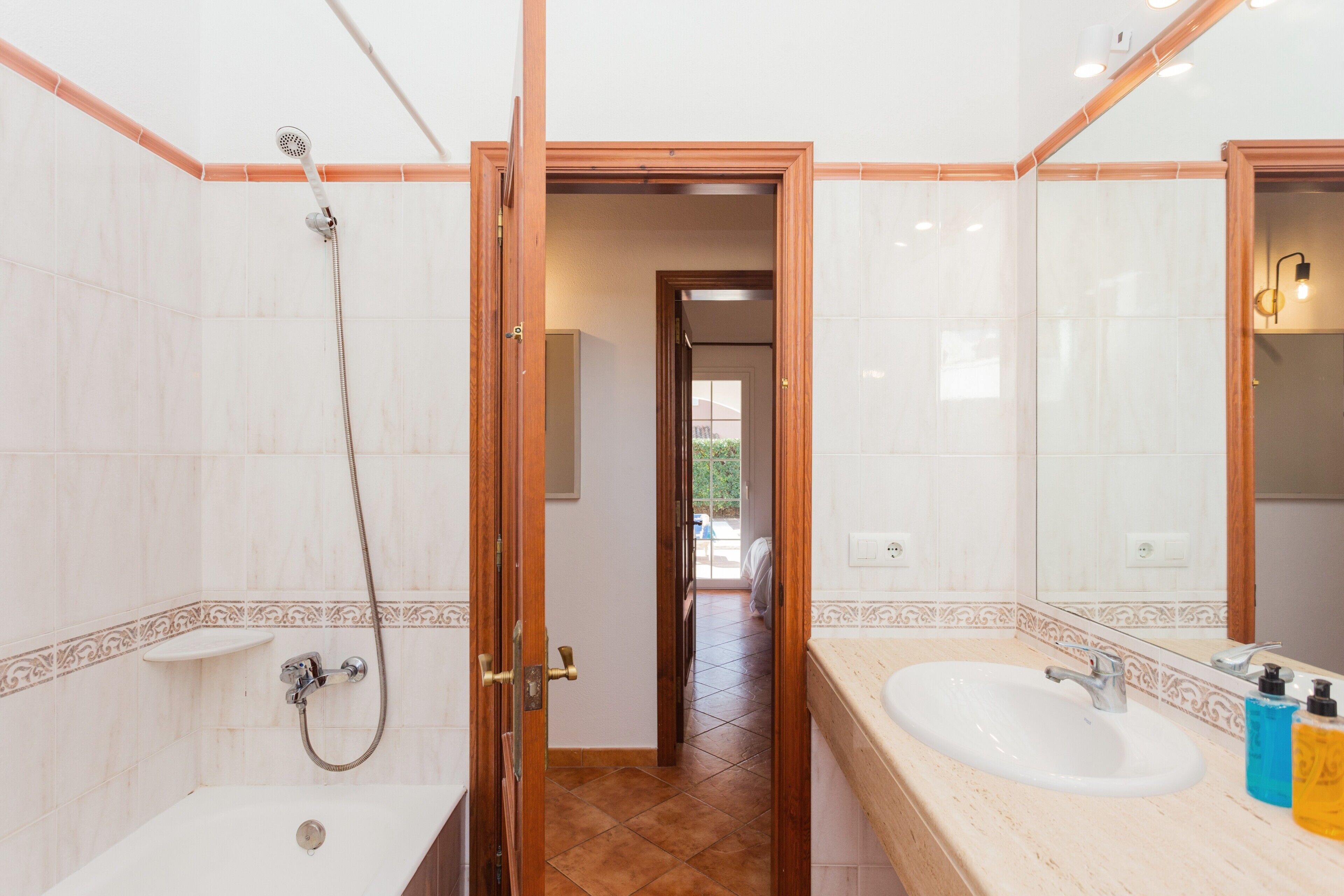 Een badkamer met douche, wastafel en spiegel.