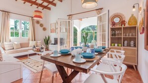 A dining area with a wooden table, white chairs, and blue dinnerware. - Chalet Villa El Pinar 5 with Pool, Wi-Fi, Terraces & Garden (Ciutadella de Menorca)