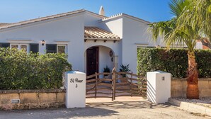 A white building with a tiled roof, a wooden gate, and a palm tree. - 'Villa El Pinar 3' with Pool, Wi-Fi, Garden & Terrace (Ciutadella de Menorca)