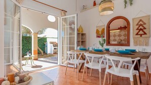A dining area with white chairs, a wooden table, and blue bowls. - 'Villa El Pinar 3' with Pool, Wi-Fi, Garden & Terrace (Ciutadella de Menorca)