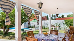A covered outdoor dining area with a pool in the background. - Pet-Friendly 'Casa Caramá' with Pool, Garden & Wi-Fi (Barbate)