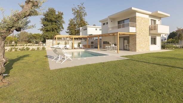 Een modern herenhuis met zwembad, terras en een gevel van natuursteen.