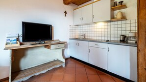 Una cocina con armarios blancos, salpicadero de azulejos, encimera de madera y un televisor sobre un mueble de madera.