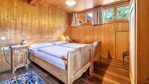 A wooden room with a bed, nightstand, and window with curtains. - Mayrhof Ahorn Apartment with Mountain View, Wi-Fi & Balcony (St. Pankraz)